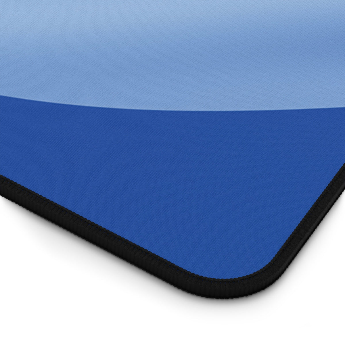 Abstract Desk Mat angled close-up of its corner revealing a blue surface and black stitched border against white.