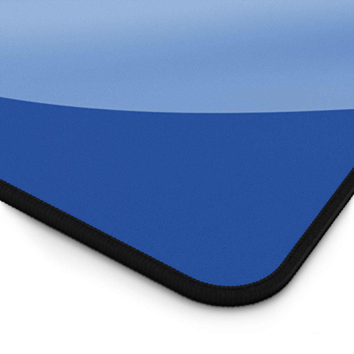 Abstract Blue Ocean Desk Mat close-up corner detail showing light-to-dark blue gradient and black stitched edge.
