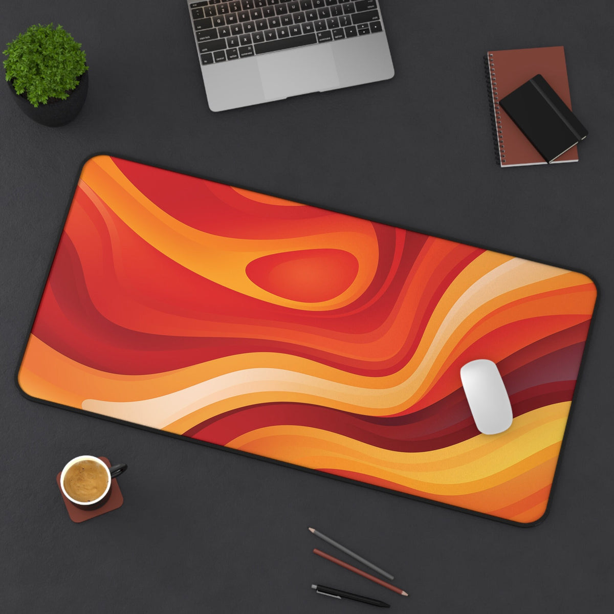 Abstract Lava Desk Mat in warm red-orange waves on a dark desk with laptop, plant, coffee and mouse, 16 × 32 inches