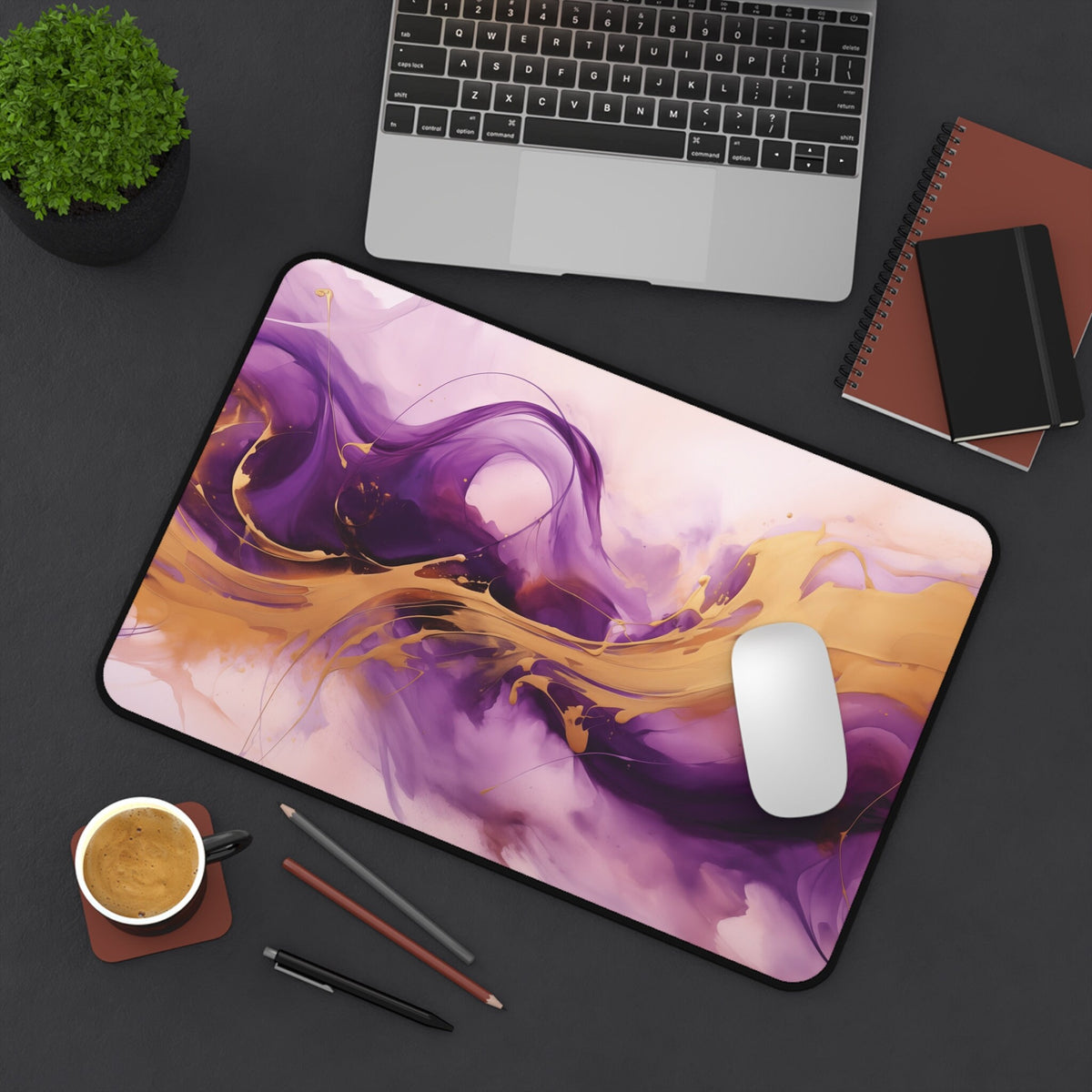 Abstract Purple And Gold Desk Mat in 12 × 18 inches on a desk with laptop, plant, coffee, pencils, notebooks and mouse.