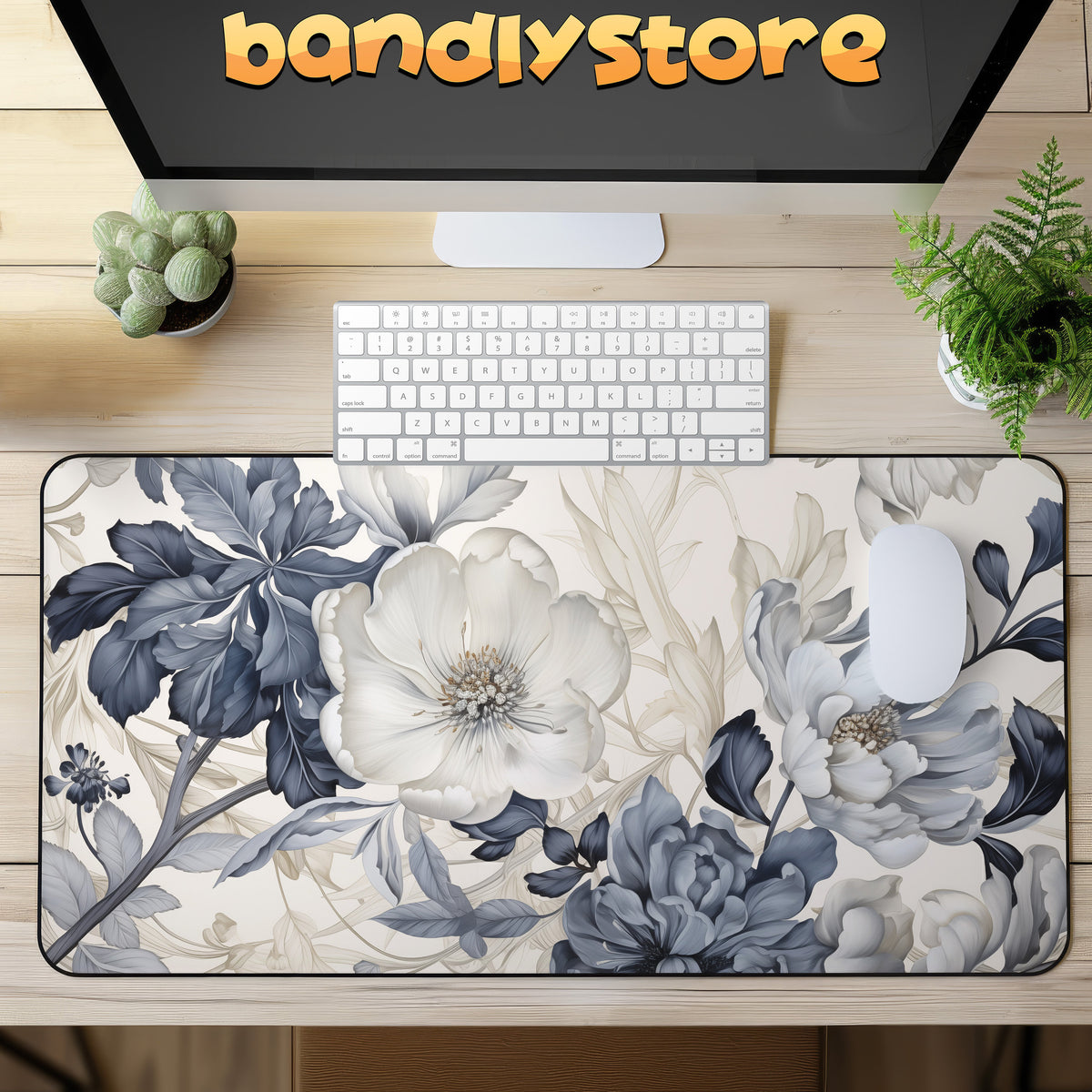 Art Nouveau Floral Desk Mat on a wooden desk with monitor, keyboard, mouse and plants in top view showing logo.
