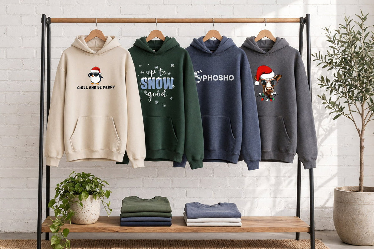 Four printed hoodies with funny sayings on wooden hangers on a wood and iron clothing rack against a sunlit white brick wall