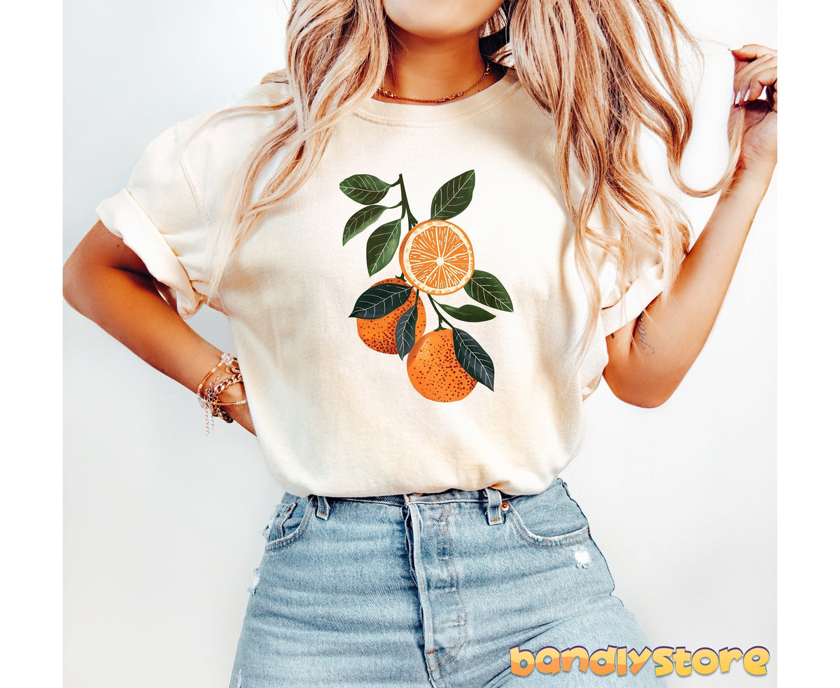 Boho Oranges T-Shirt in ivory worn front-facing by a blonde model in jeans against a plain white backdrop.