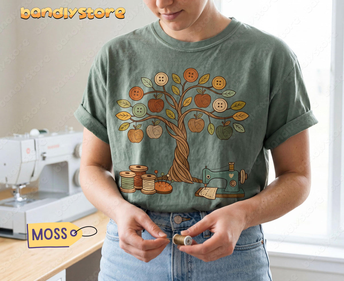 Boho Sewing T-Shirt in Moss worn front-on by a person holding a spool beside a sewing machine.