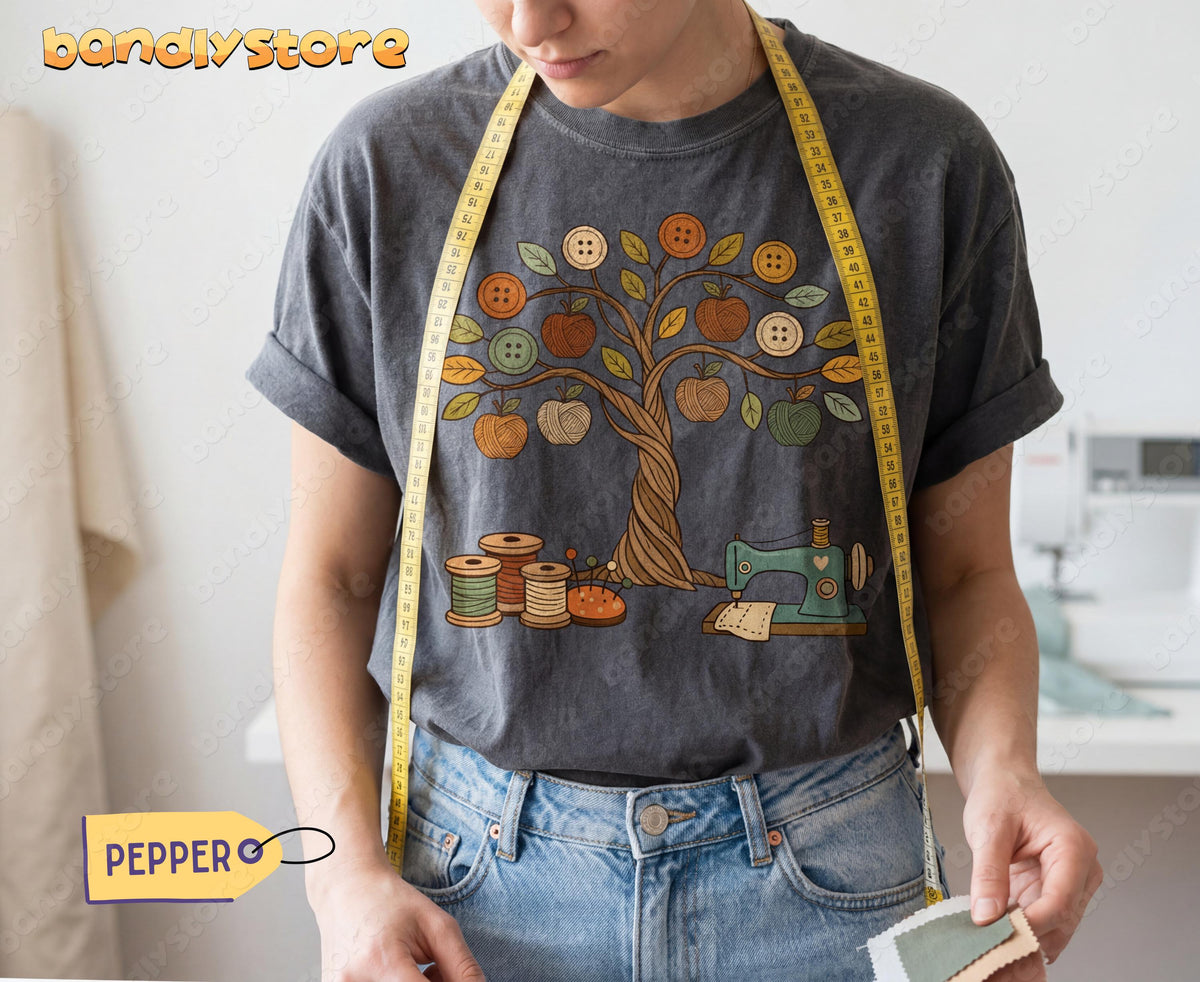 Boho Sewing T-Shirt worn front-on with measuring tape over shoulders, hands holding fabric samples by a sewing machine in Pepper