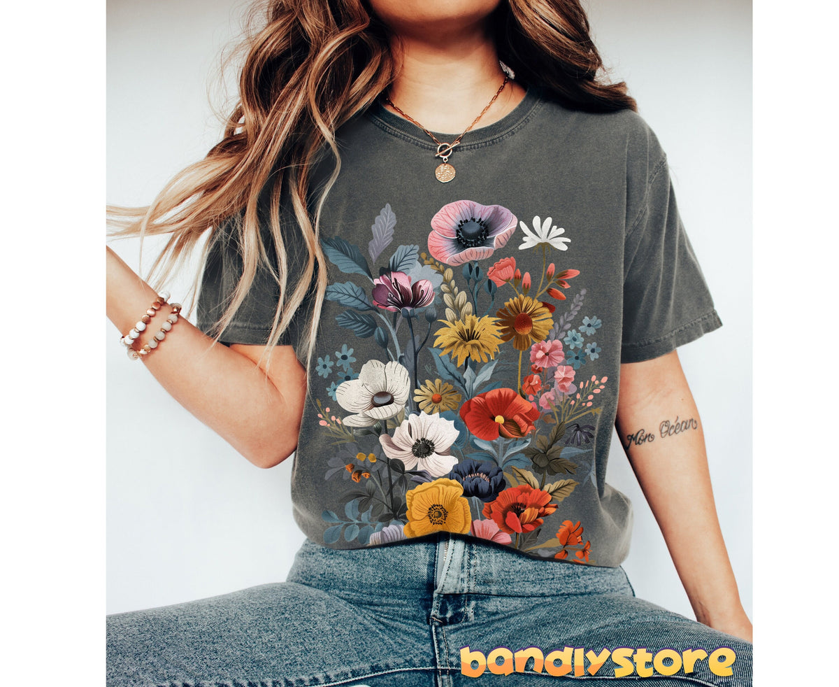 Boho Wildflowers T-Shirt in Pepper, worn front-facing with jeans, layered necklaces, bracelets and a forearm tattoo visible.