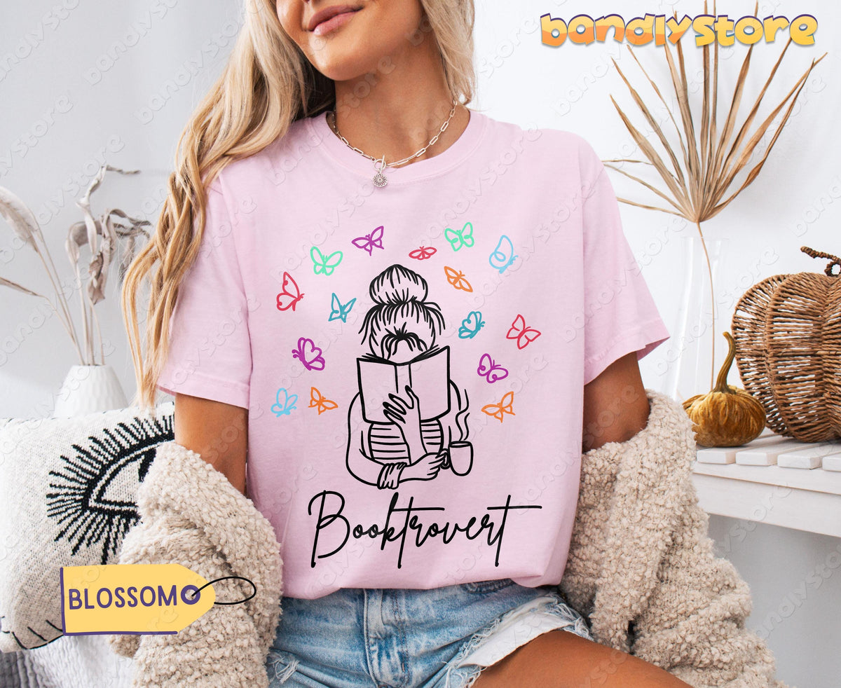 Booktrovert T-Shirt in Blossom on a seated model amid dried plants, basket and pumpkins.
