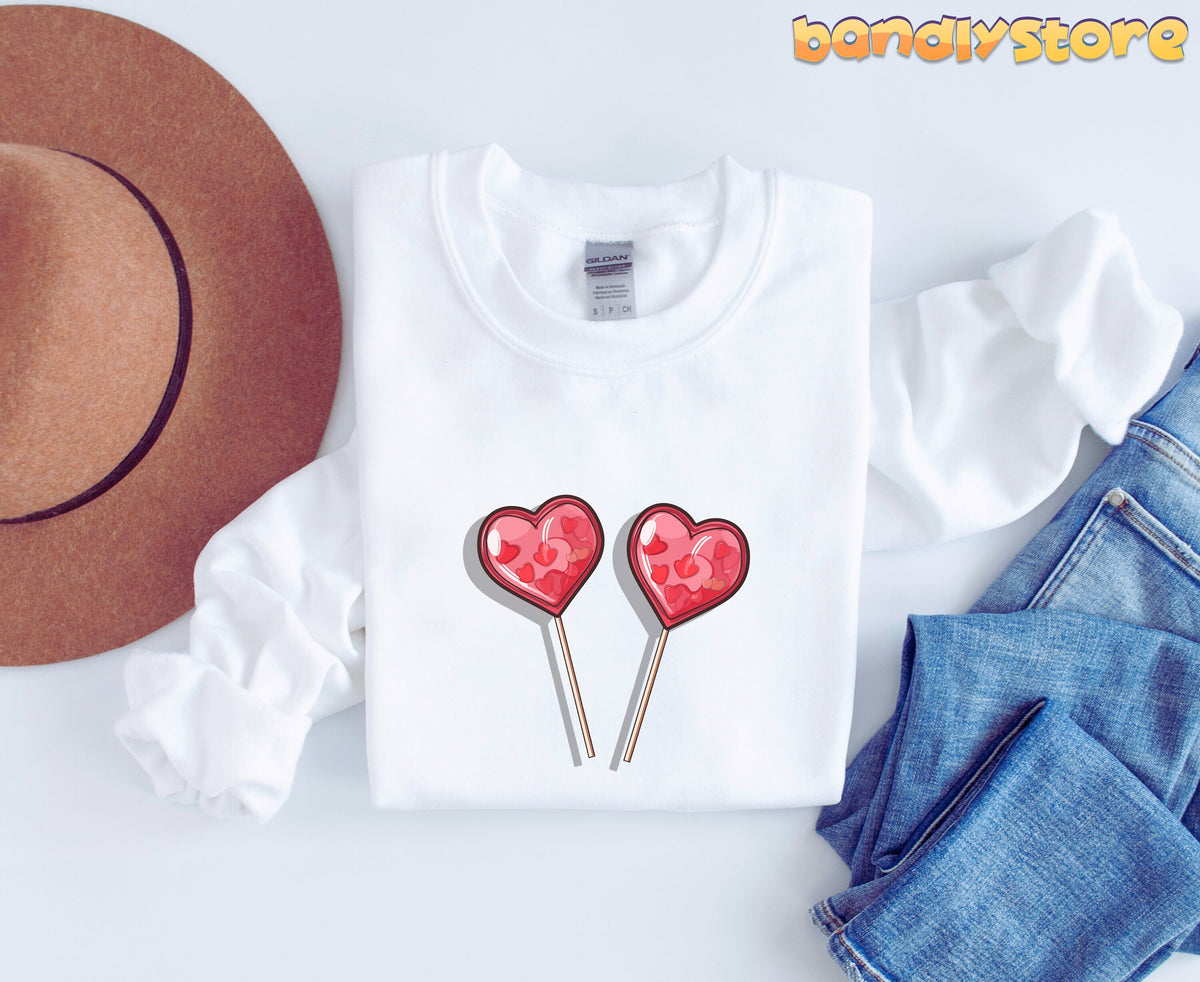 Cute Candy Hearts Sweatshirt white garment flat-laid with brown hat left and blue jeans right.