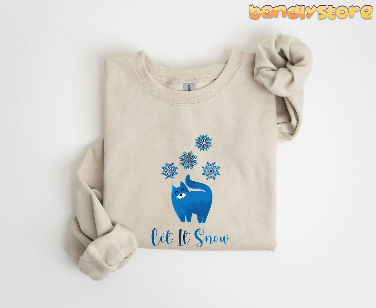 Christmas Cat Let It Snow Sweatshirt in sand, folded flat on a plain white background from above.
