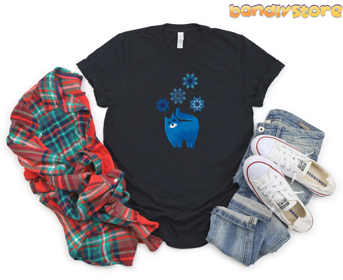 Christmas Cat and Snowflakes T-Shirt in black, flat-lay with plaid shirt left and jeans with white sneakers right.