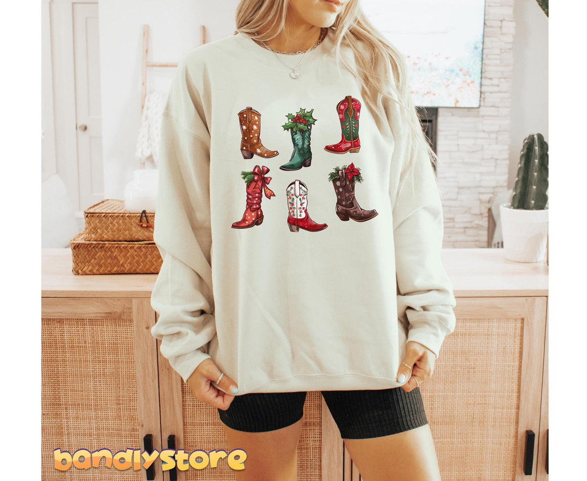Christmas Cowgirl Boots Sweatshirt in sand on a person facing forward in a room with wooden cabinets, baskets and cactus.