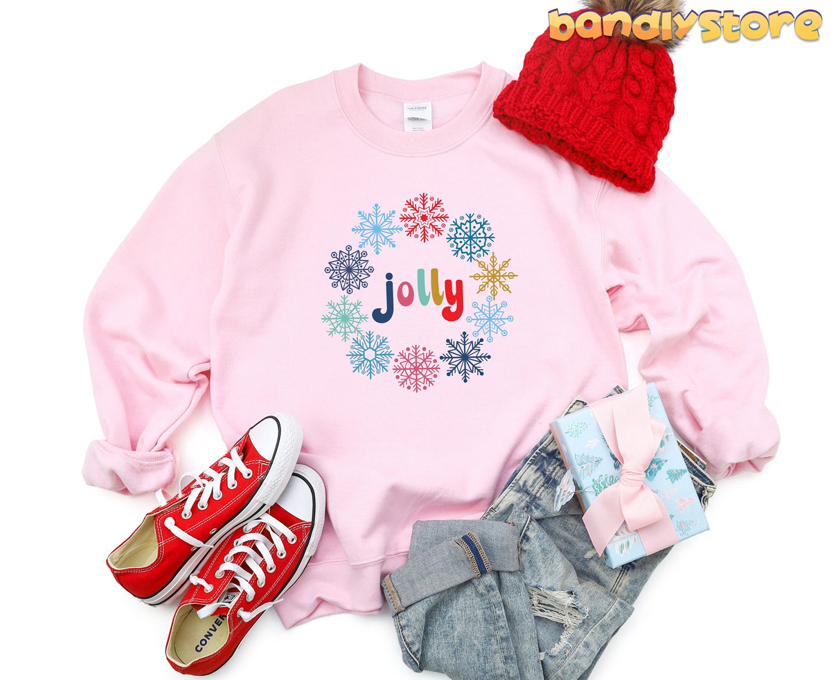 Jolly Snowflake Sweatshirt in light pink laid flat with red beanie, red sneakers, jeans and gift box.