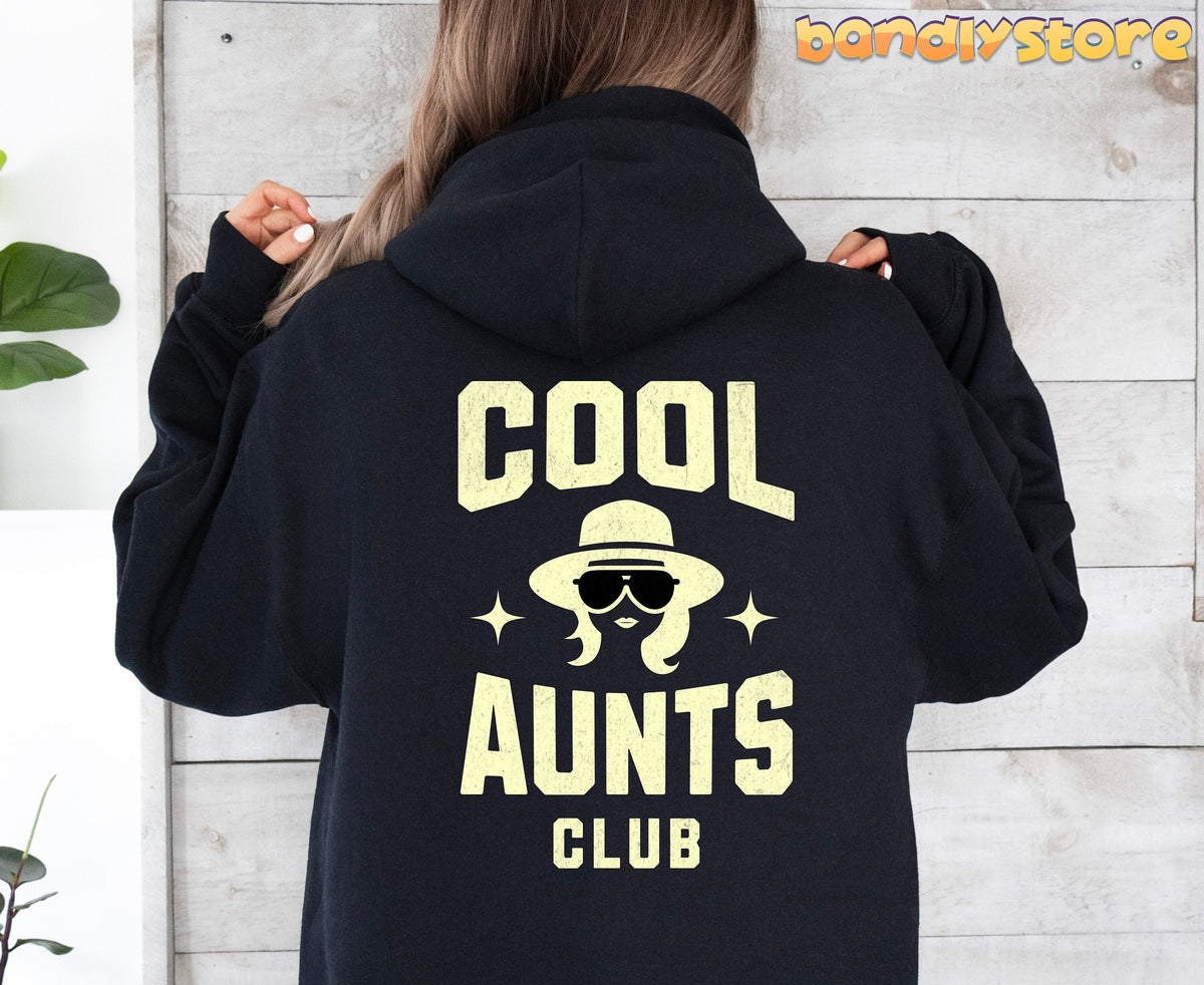 Cool Aunts Club Hoodie in black worn from behind by a person against a light wood wall with plants.