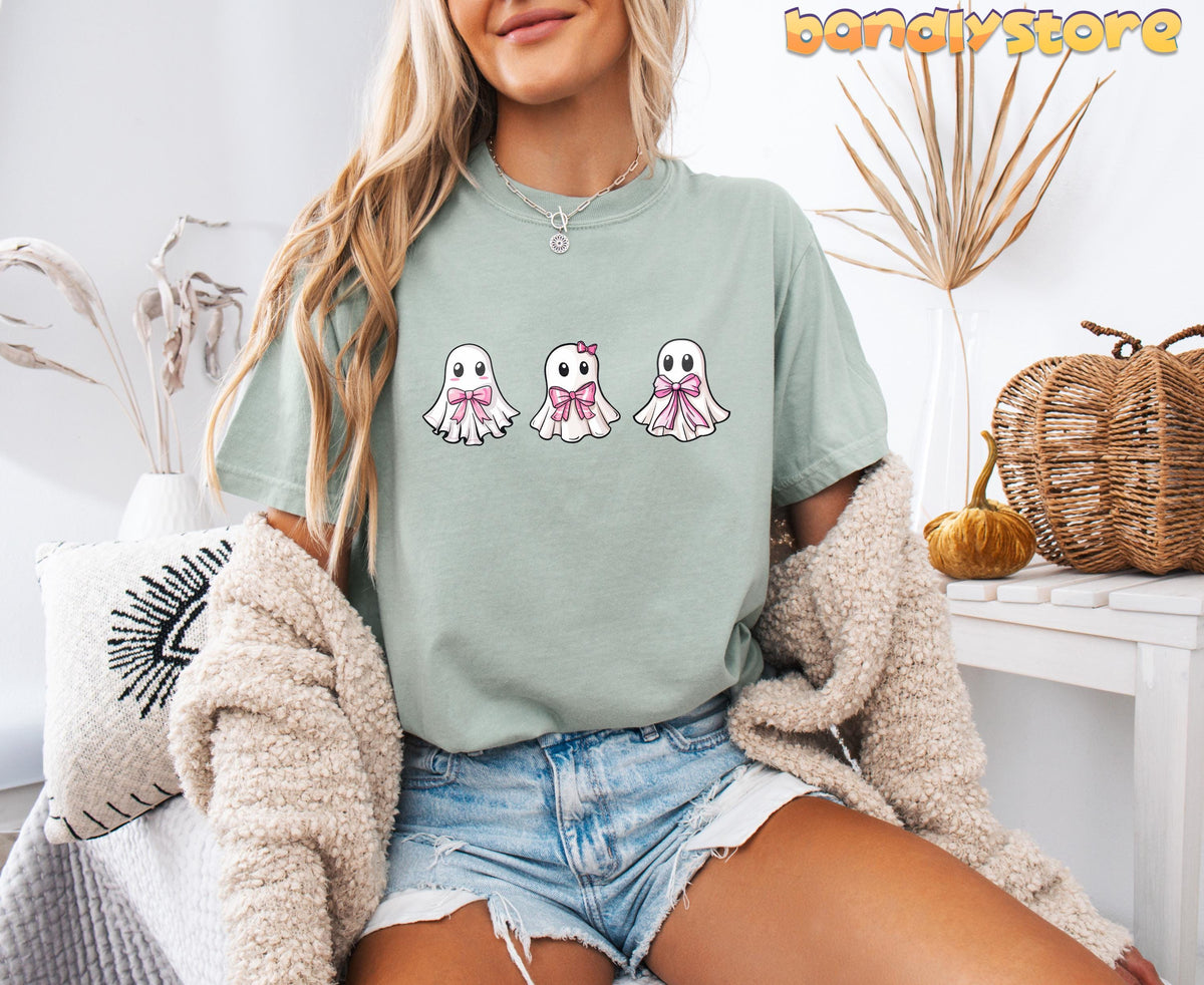 Cute Coquette Ghost T-Shirt in bay on a seated woman amid dried plants, pillow and pumpkin.