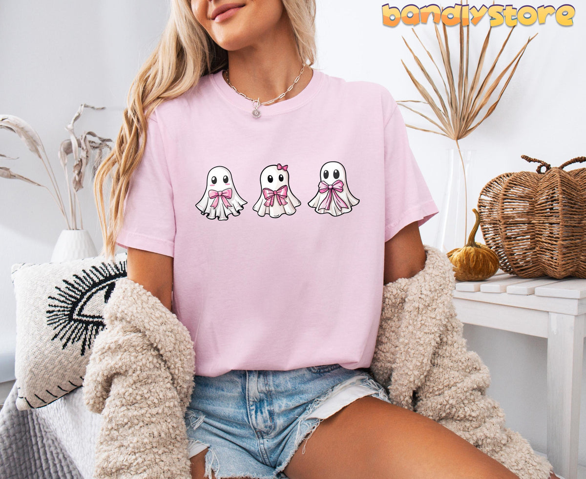Cute Coquette Ghost T-Shirt in Blossom on a seated model amid dried plants, pumpkins and a wicker basket.