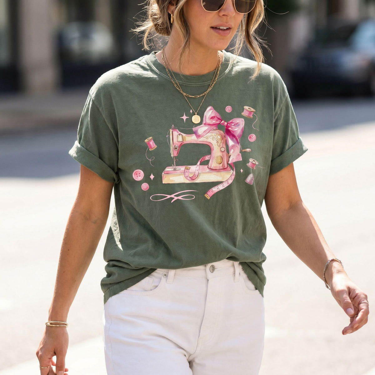 Coquette Sewing T-Shirt in moss on a woman walking a city street, front torso view with sewing graphic.