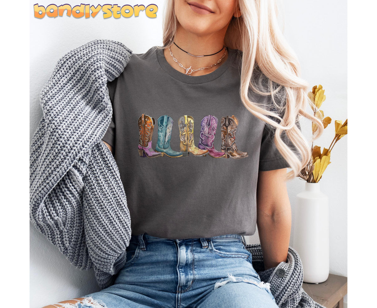 Cowgirl Boots T-Shirt in Asphalt on a seated model with gray knit sweater, jeans, and white vase nearby.
