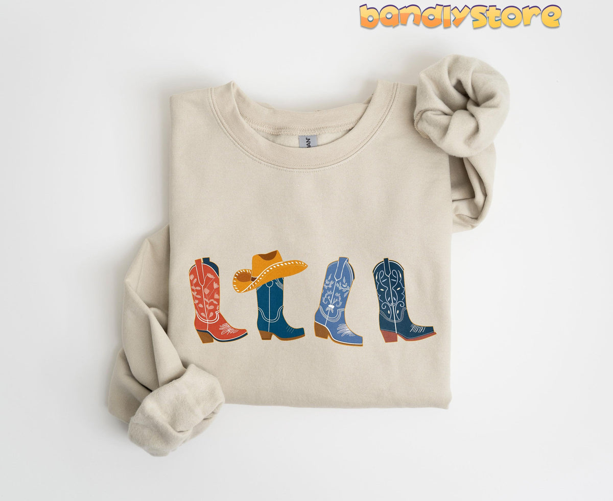 Cowgirl Boots Sweatshirt in sand, folded flat on white with four colorful cowboy boots printed across the chest.