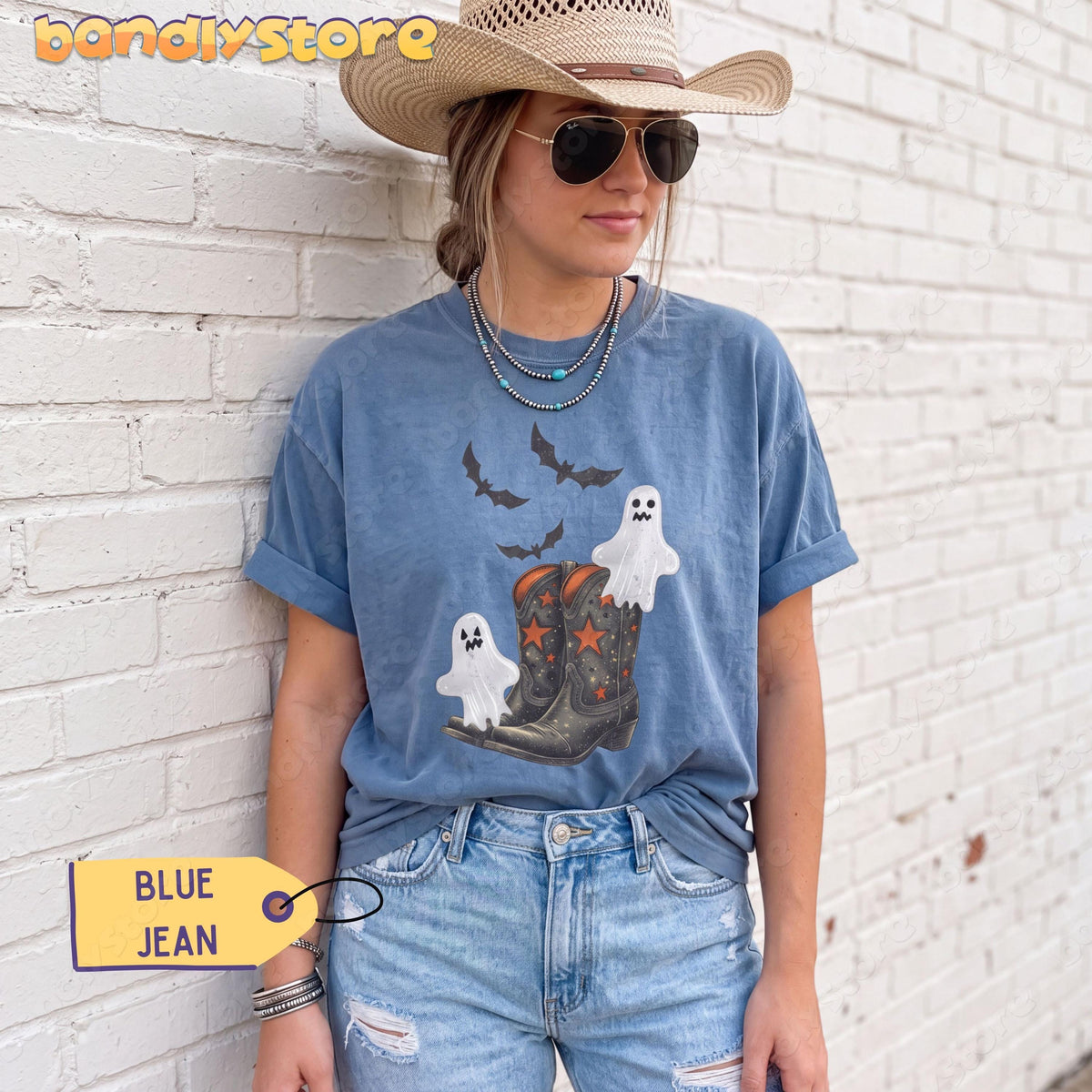 Vintage Cowgirl Boots and Ghosts T-Shirt in Blue Jean worn by a woman leaning against a white brick wall.