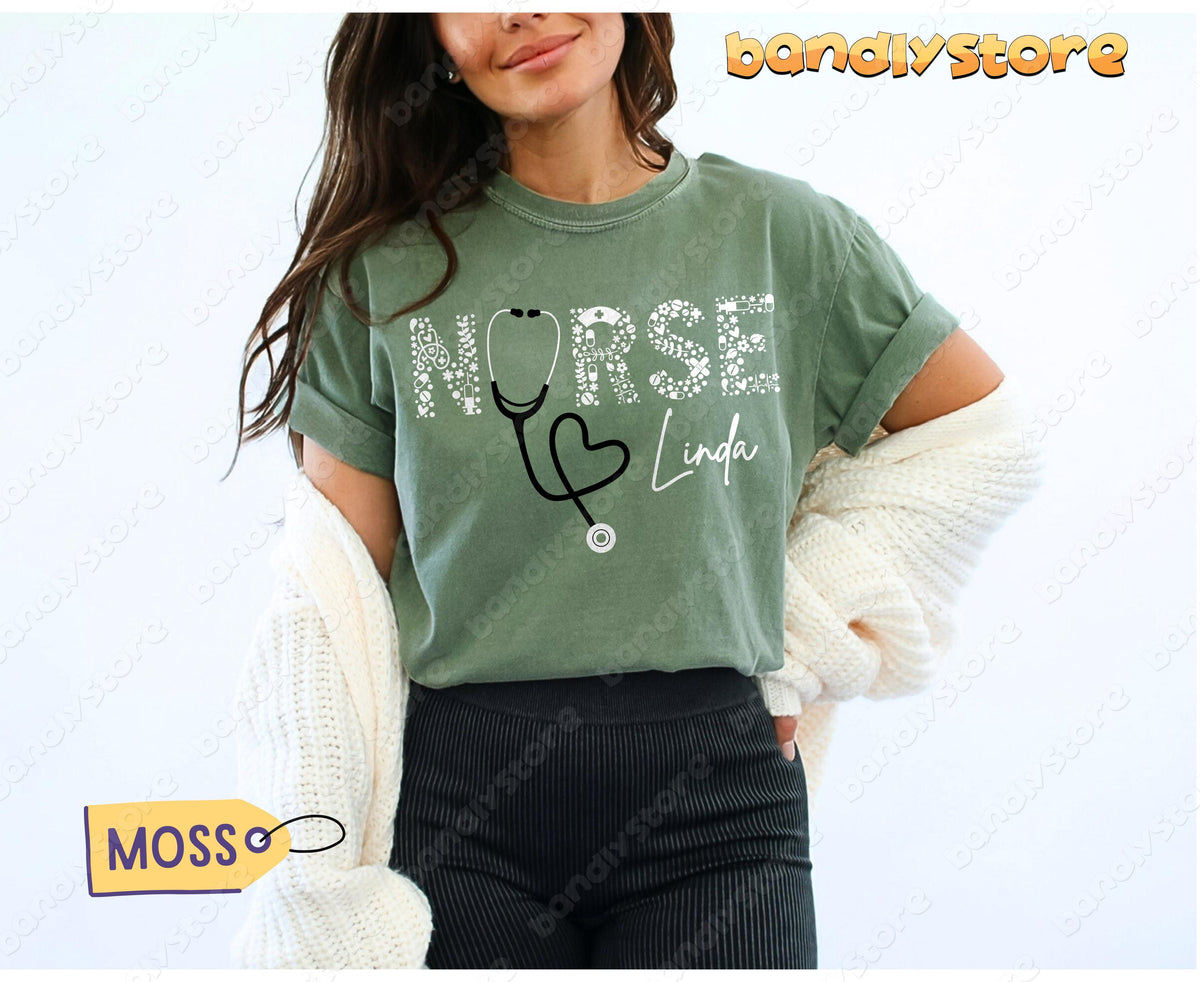 Custom Name Nurse T-Shirt in moss on a model facing forward holding a knit sweater against light background.