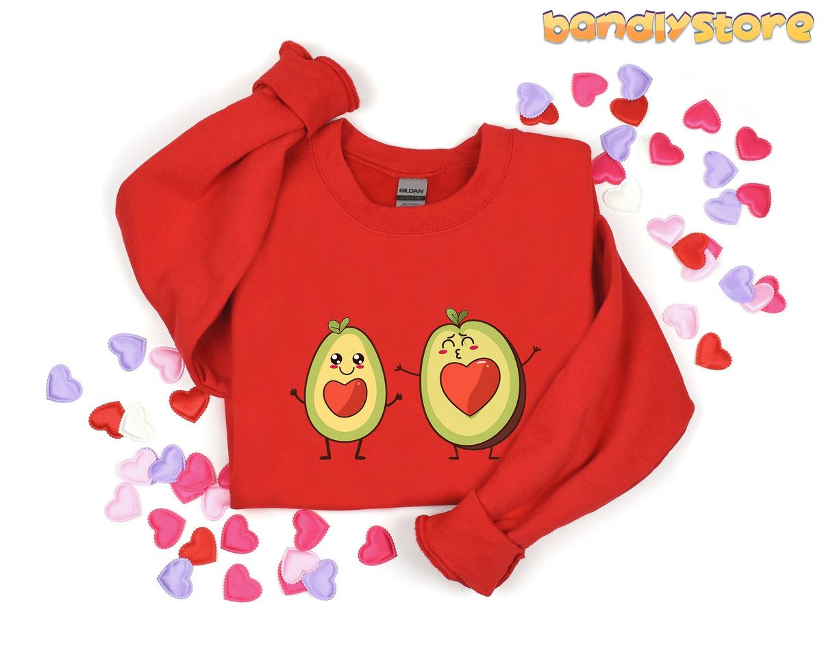 Cute Avocado Love Sweatshirt in red flat-laid on white with scattered heart confetti.
