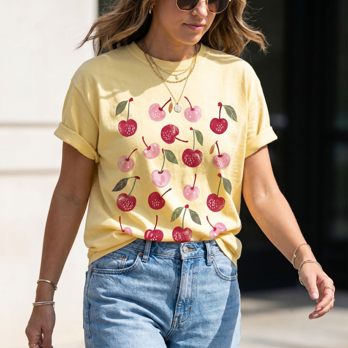 Cute Cherry T-Shirt in butter on a woman outdoors wearing jeans and sunglasses.
