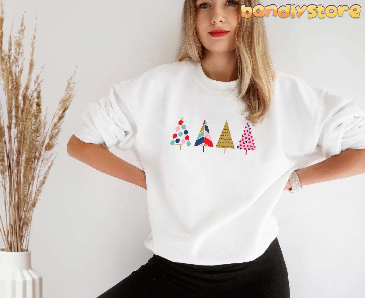 Cute Christmas Trees Sweatshirt in white, front view on a model with dried grass in a vase nearby.