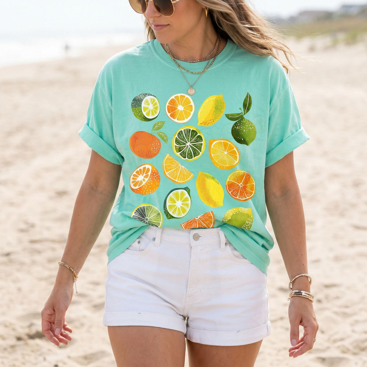 Cute Lemons And Oranges T-Shirt in Island Reef worn by a woman standing on a sandy beach.