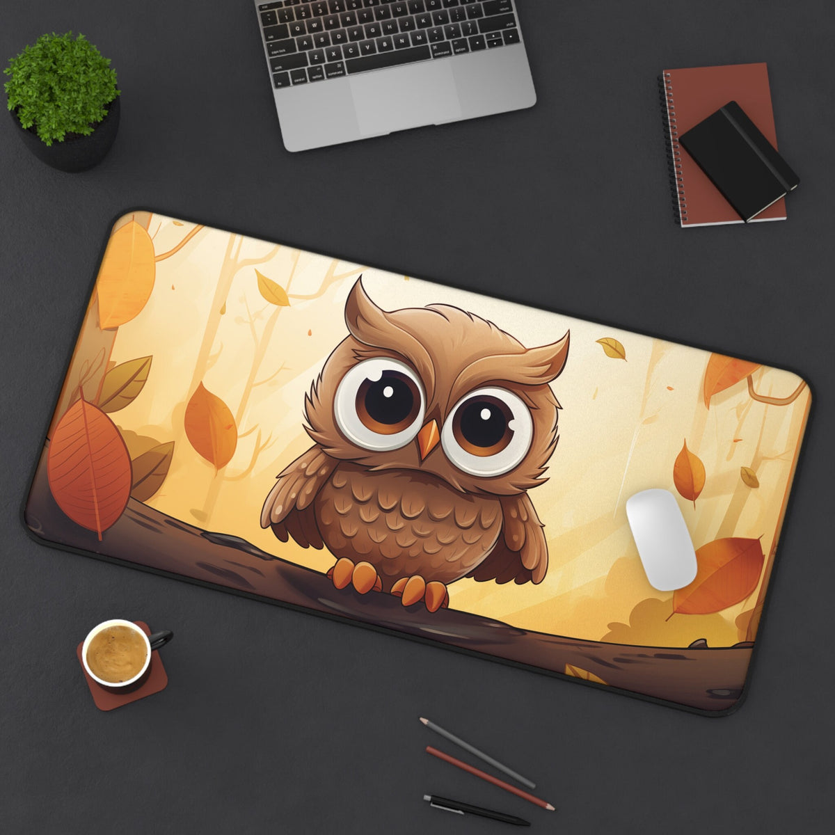 Cute Owl Autumn Desk Mat 16 × 32 inches in top-down view on dark desk with laptop, plant, notebooks, coffee and pens.