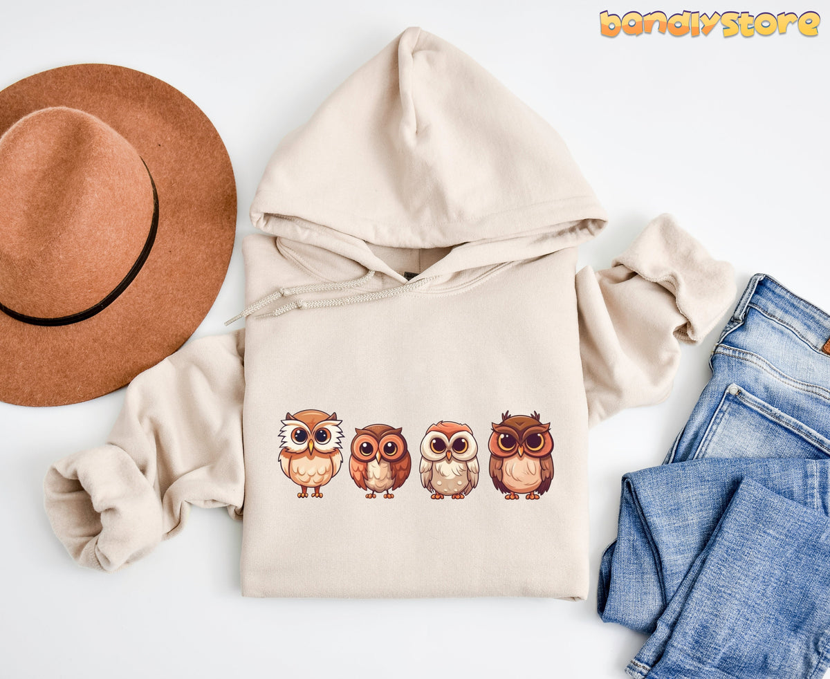 Cute Owl Hoodie in sand laid flat from above beside a brown hat and blue jeans.