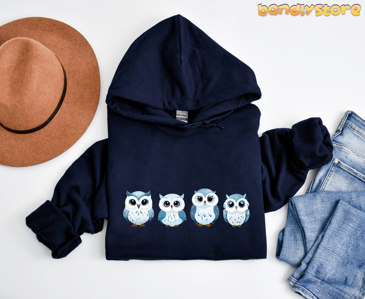 Cute Snow Owl Hoodie in navy, flat-lay with brown hat left and blue jeans right on white background.