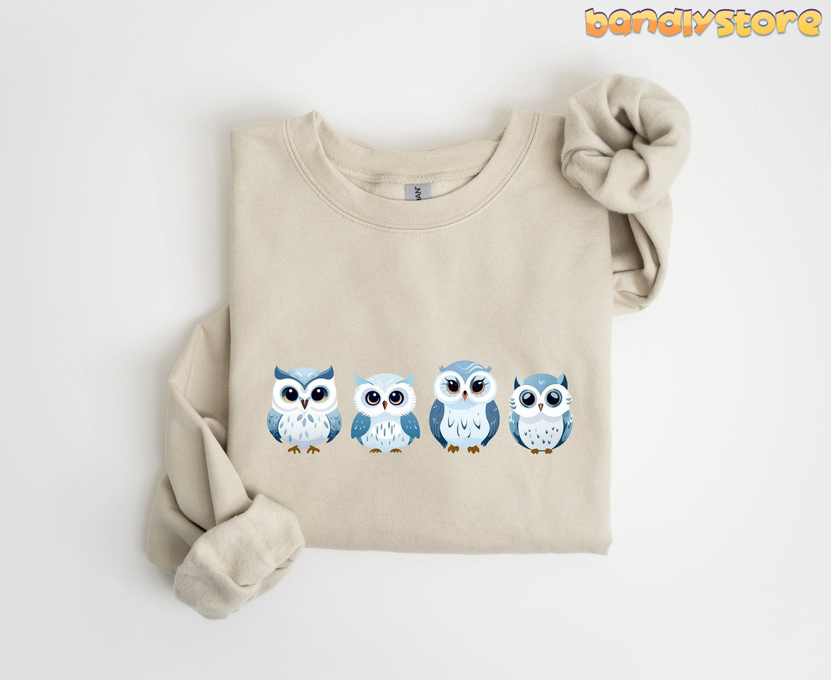 Cute Snow Owl Sweatshirt in sand folded flat on white background showing four owl designs.