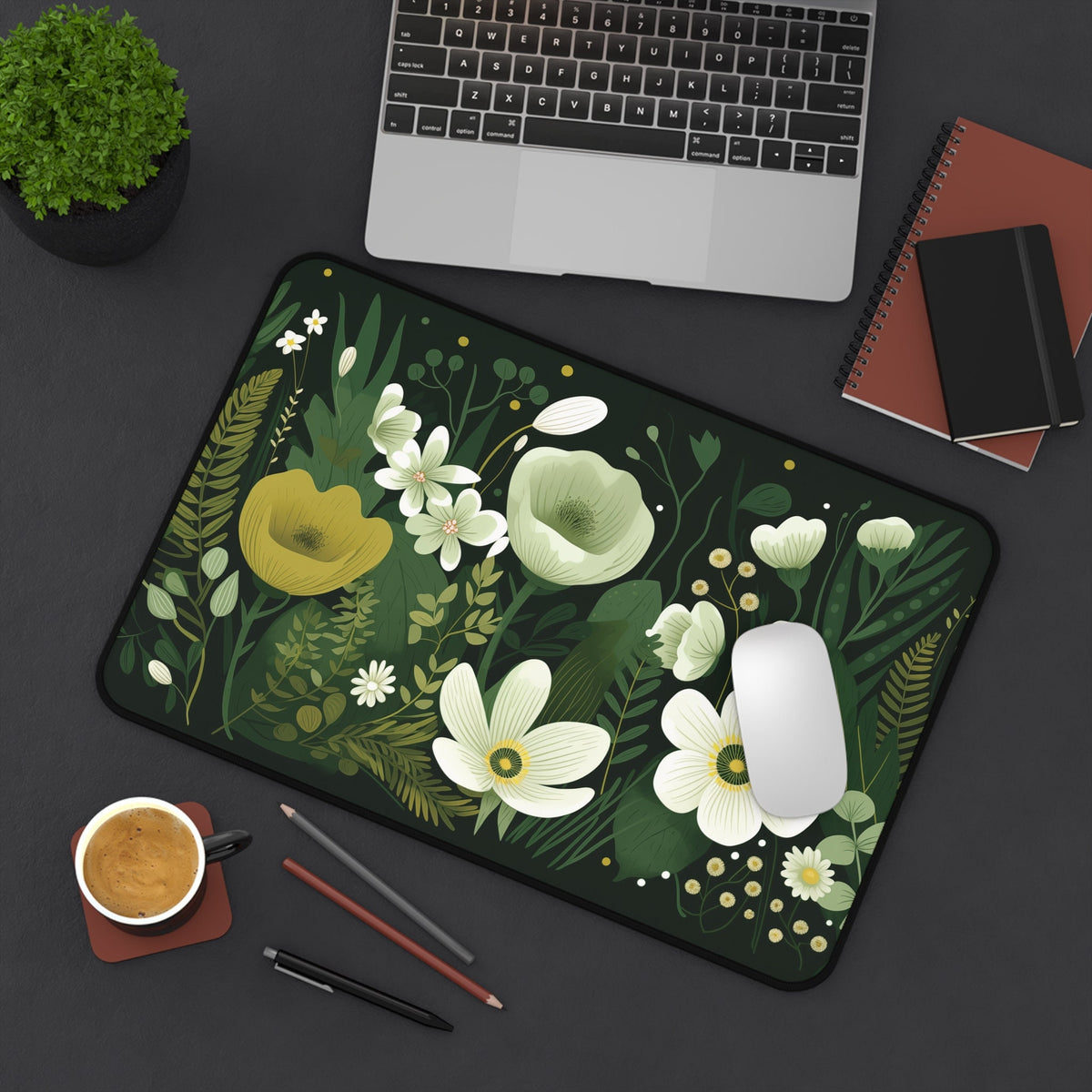 Dark Floral Desk Mat in overhead view on a desk with laptop, plant, coffee, pens, notebooks and mouse, 12 × 18 inches.