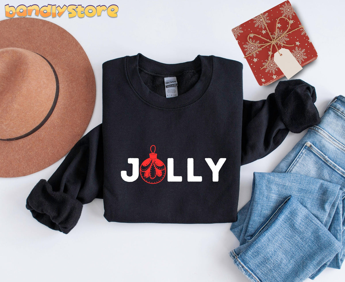 Feeling Jolly Christmas Sweatshirt in black, overhead flat lay with brown hat, blue jeans and red gift.