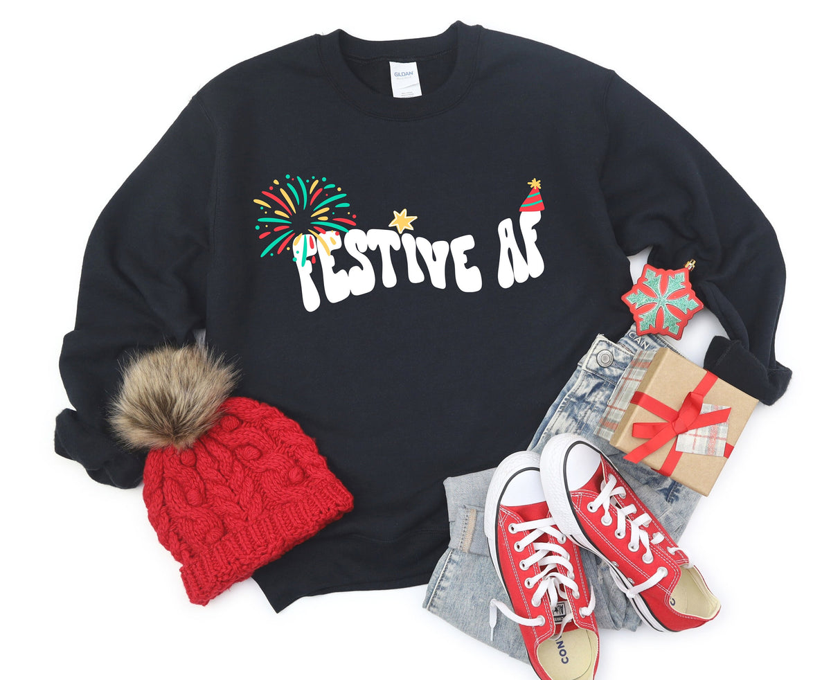 Festive AF Sweatshirt in black flat lay with red beanie, sneakers, jeans, gift box and ornament.