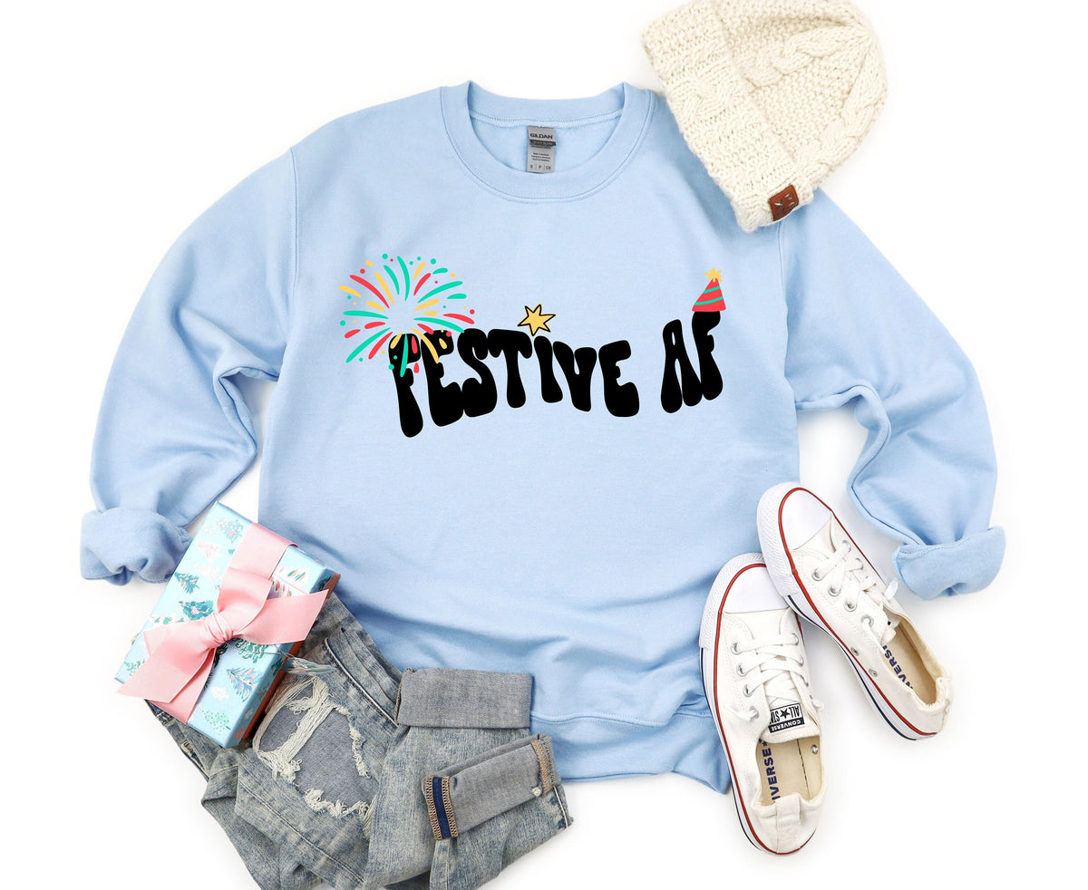 Festive AF Sweatshirt in light blue flat-laid with beanie, gift, jeans and sneakers nearby.