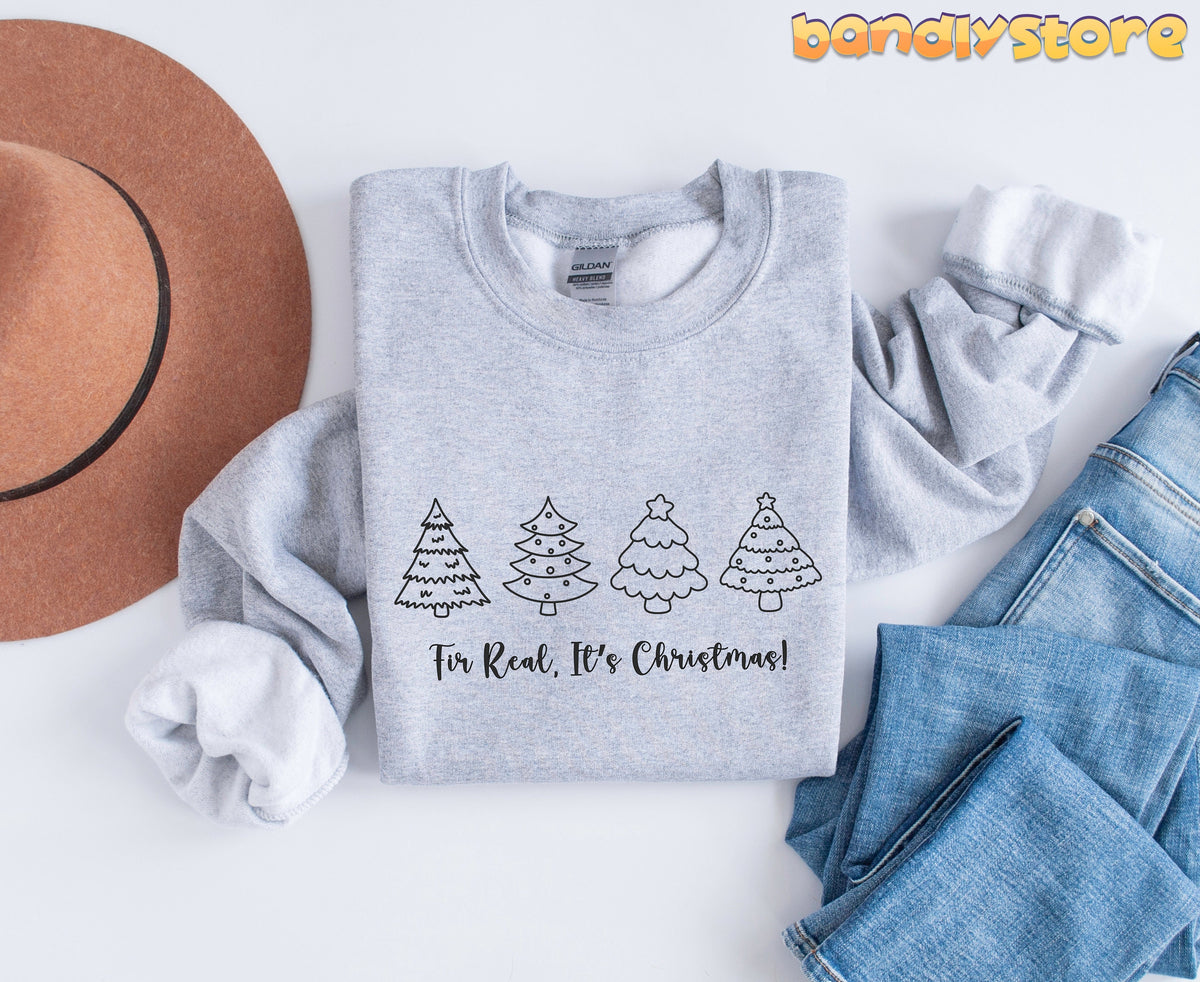 Fir Real It's Christmas Sweatshirt in Sport Grey, flat-laid with hat left and jeans right, four line-art trees and slogan.