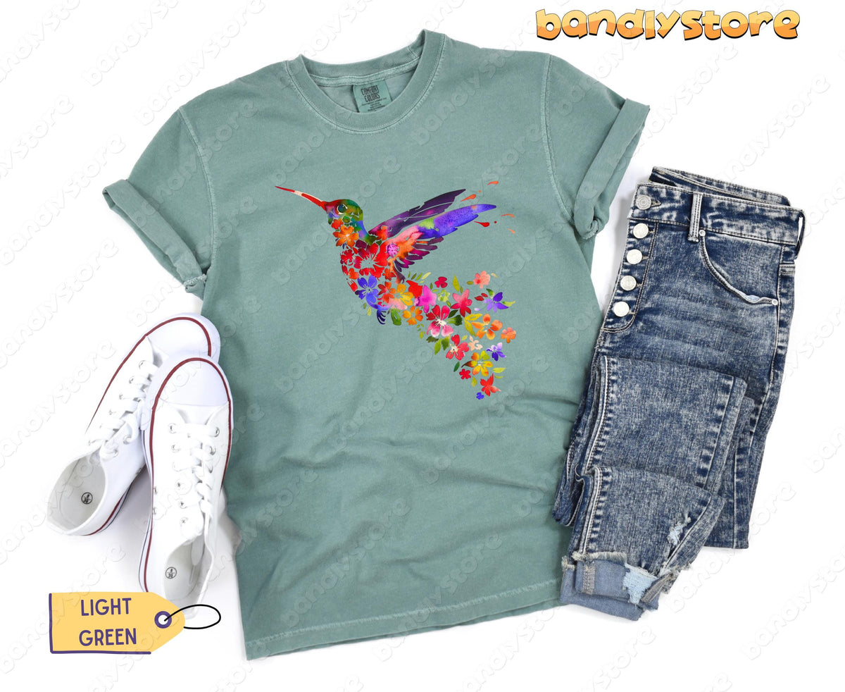Floral Hummingbird T-Shirt in light green flat-laid from above next to white sneakers and blue jeans.