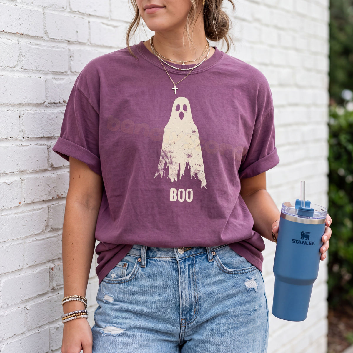 Grungy Ghost T-Shirt in Berry on a person against a white brick wall holding a blue tumbler.