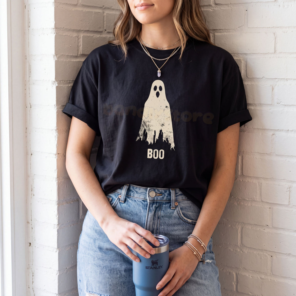 Grungy Ghost T-Shirt in black, worn by a person leaning on a white brick wall holding a blue tumbler.