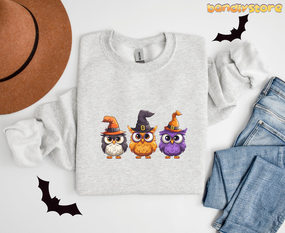 Halloween Owl Sweatshirt in ash flat-laid from above beside a brown hat, jeans and bat cutouts.