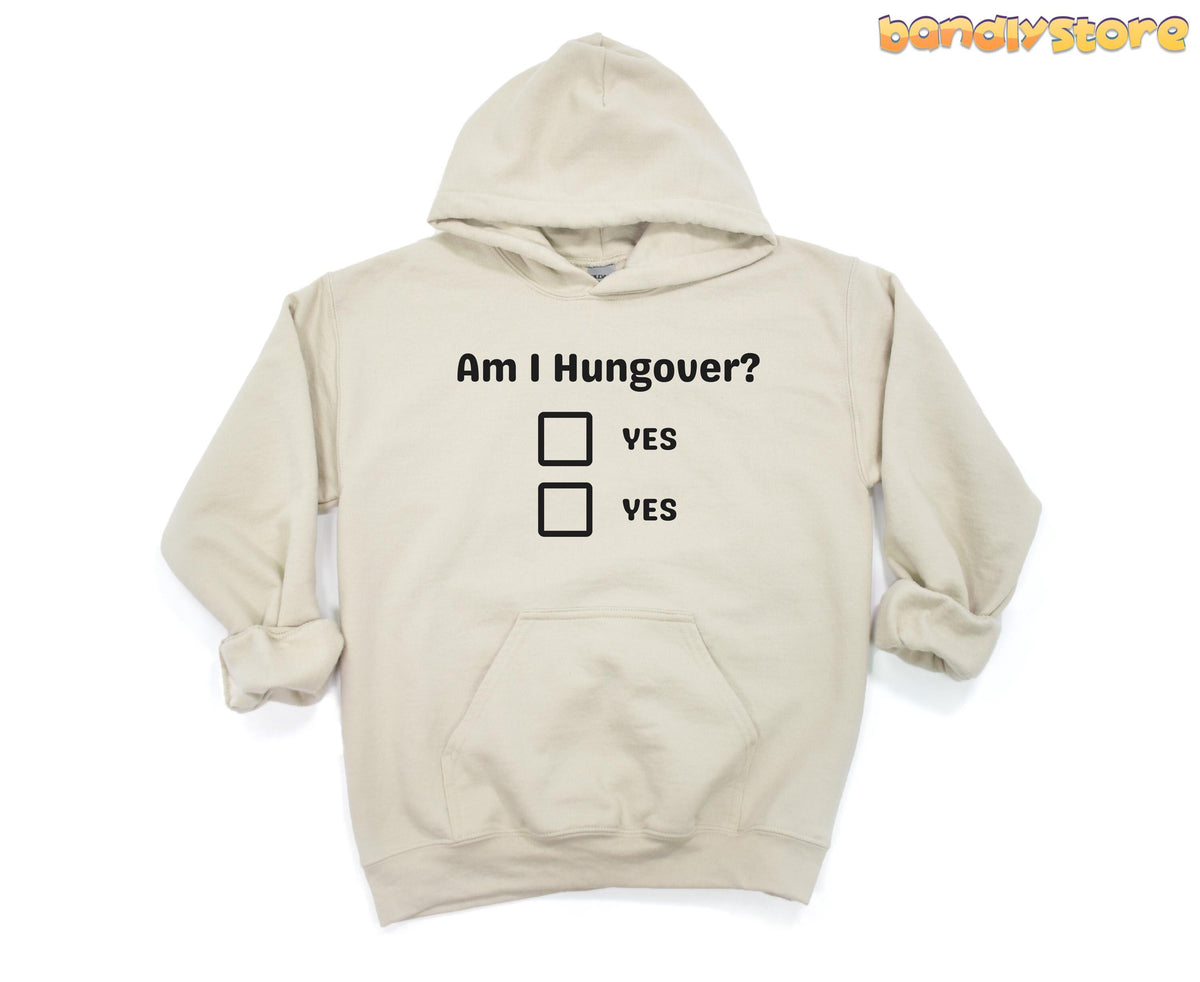 Hangover Hoodie sand garment laid flat on white, hood up, front text Am I Hungover? with two YES boxes.