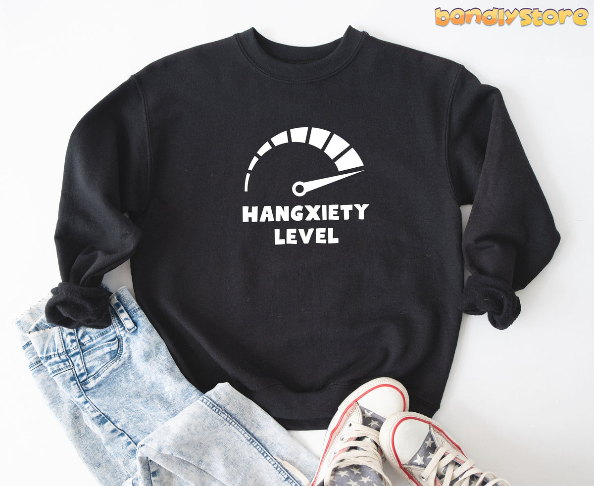 Hangxiety Hangover Sweatshirt in black laid flat on white beside jeans and sneakers.