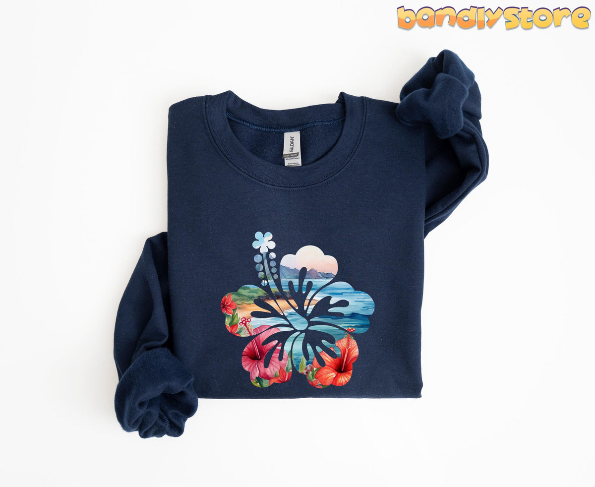 Hawaii Hibiscus Sweatshirt on navy fabric, folded flat with sleeves knotted, beach scene and hibiscus flowers on white.
