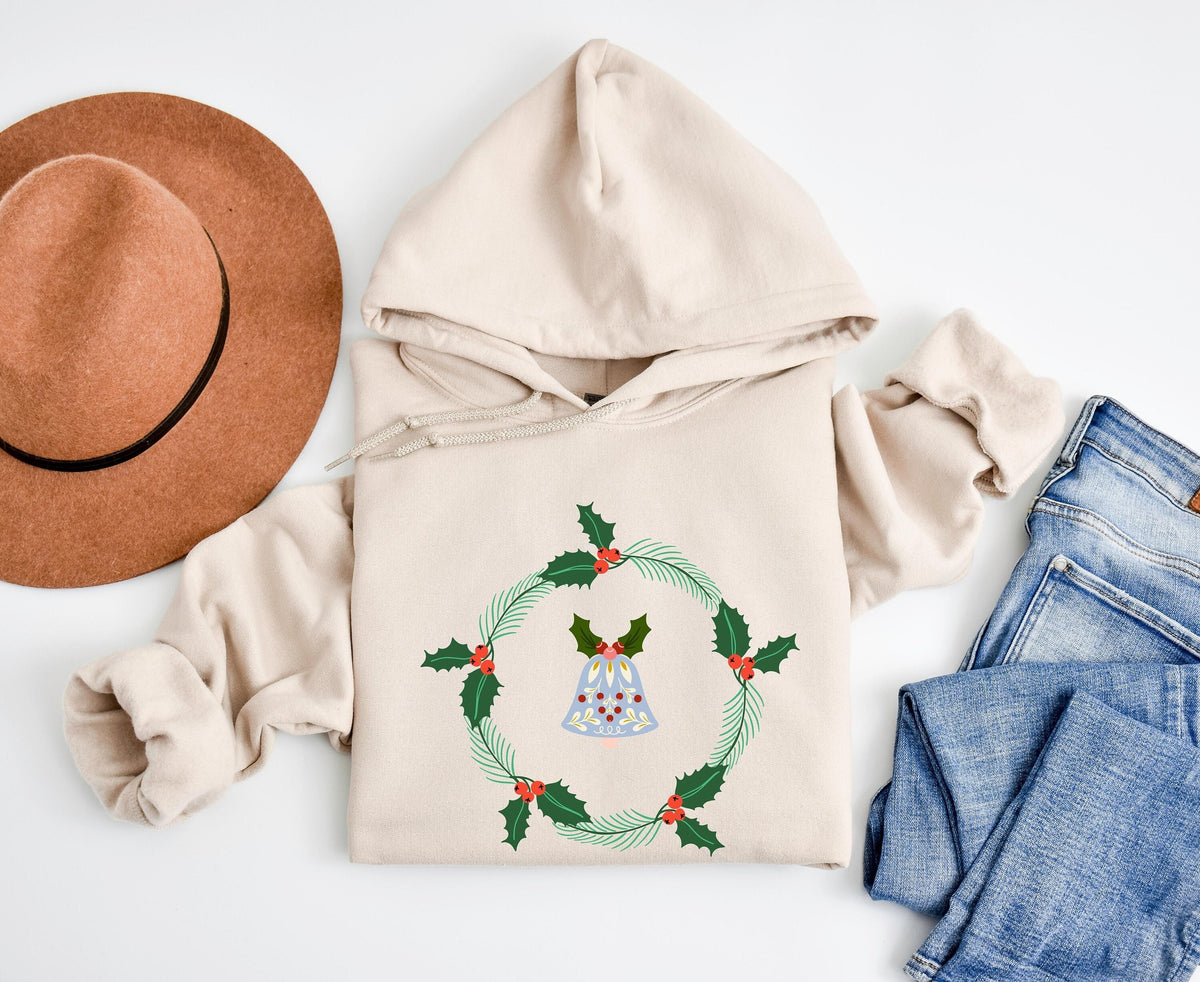 Holly Wreath Hoodie in sand, top-down flat lay on white with brown hat and blue jeans beside it.