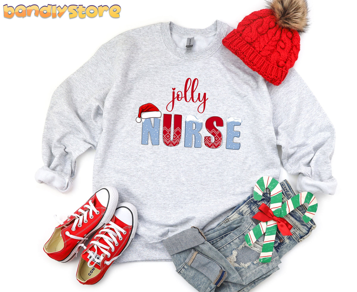 Jolly Nurse Sweatshirt in ash flat-laid from above on white beside red beanie, sneakers, jeans and candy canes.