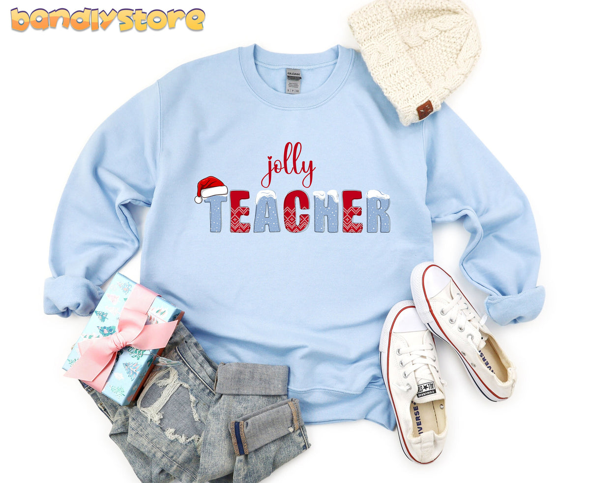 Jolly Teacher Sweatshirt in light blue laid flat with beanie, gift, jeans and sneakers around it.
