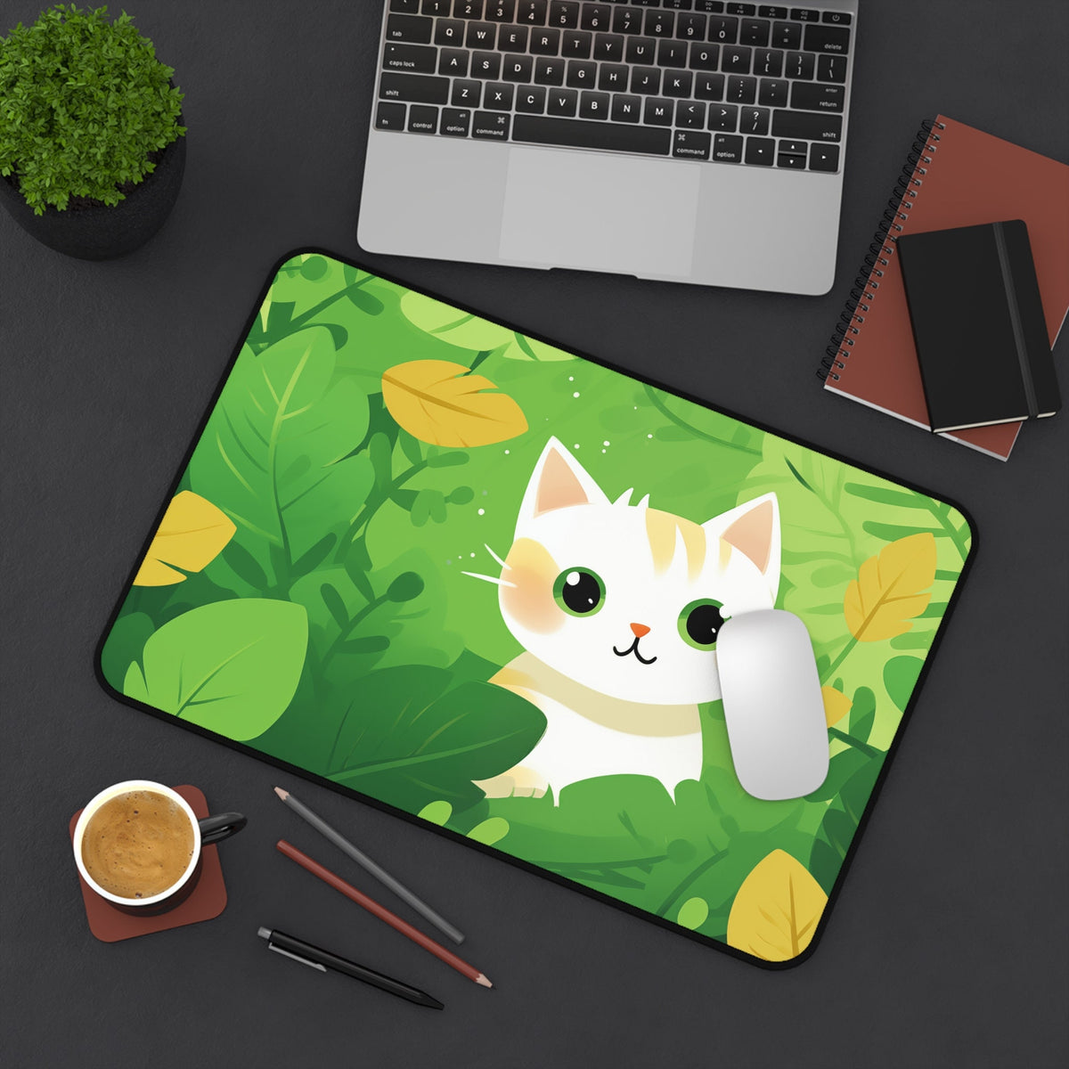 Cute Kawaii Cat Desk Mat from above on a desk with a laptop, plant, coffee, pens, notebooks and mouse, 12 × 18 inches.