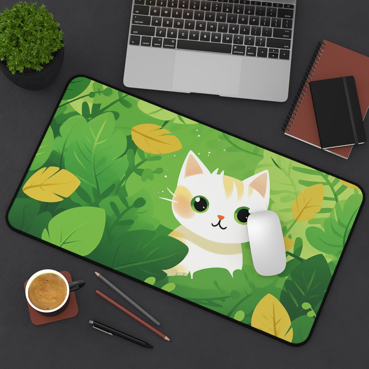 Cute Kawaii Cat Desk Mat top-down on dark desk by laptop, plant, notebooks, coffee, pencils and mouse, 12 × 22 inches.