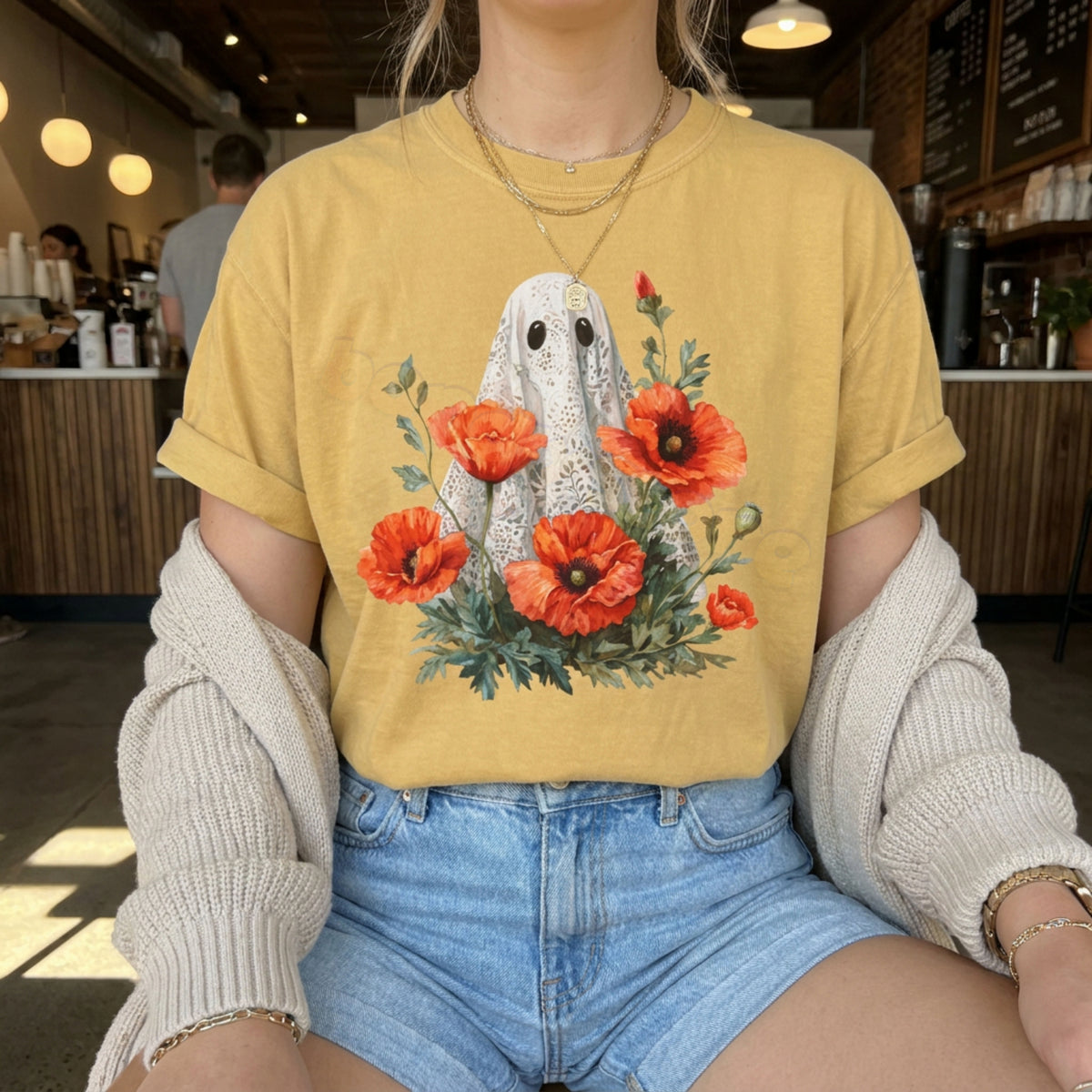 Vintage Lace Ghost Poppies T-Shirt in mustard on seated person in cafe, front angle with counter behind.
